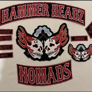 May include: A collection of embroidered patches with a biker theme. The patches feature skulls, flames, and the words "HAMMER HEADZ," "NOMADS," "BAD BOYS," and "PRESIDENT" in red and white on a black background.