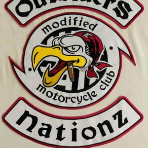 May include: Embroidered motorcycle club patches with the text "Outsider's modified motorcycle club Nationz". The patches feature a white background with black and red accents, and a cartoon eagle with a cigar.