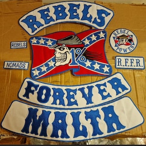 May include: A selection of embroidered patches with a biker theme. The patches feature the words "REBELS", "NOMADS", "FOREVER", and "MALTA" in blue lettering. A central patch displays a skull wearing a hat on a red and white flag.