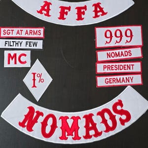 Puede incluir: Un conjunto de parches bordados con letras rojas sobre fondo blanco. Los parches incluyen las palabras "AFFA", "999", "NOMADS", "PRESIDENT" y "GERMANY". Otros parches dicen "SGT AT ARMS", "FILTHY FEW", "MC" y "1%".