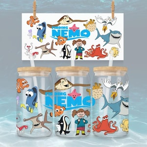 May include: Three glass tumblers with Finding Nemo character designs. Each tumbler has a wooden lid and a straw. The design includes Nemo, Dory, Crush, and other characters from the movie. A matching sign hangs above the tumblers.