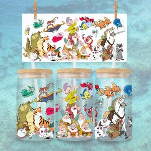 Op de afbeelding: Drie glazen bekers met houten deksels en rietjes, elk met een ander cartoonkarakterontwerp. De ontwerpen omvatten personages uit verschillende animatiefilms. Een bijpassende print hangt boven de bekers, vastgehouden door wasknijpers.