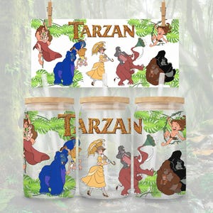 May include: Three glass tumblers with wooden lids and straws, featuring a "Tarzan" theme. The tumblers are decorated with cartoon characters and the word "Tarzan". A matching sign hangs above the tumblers with the same design.