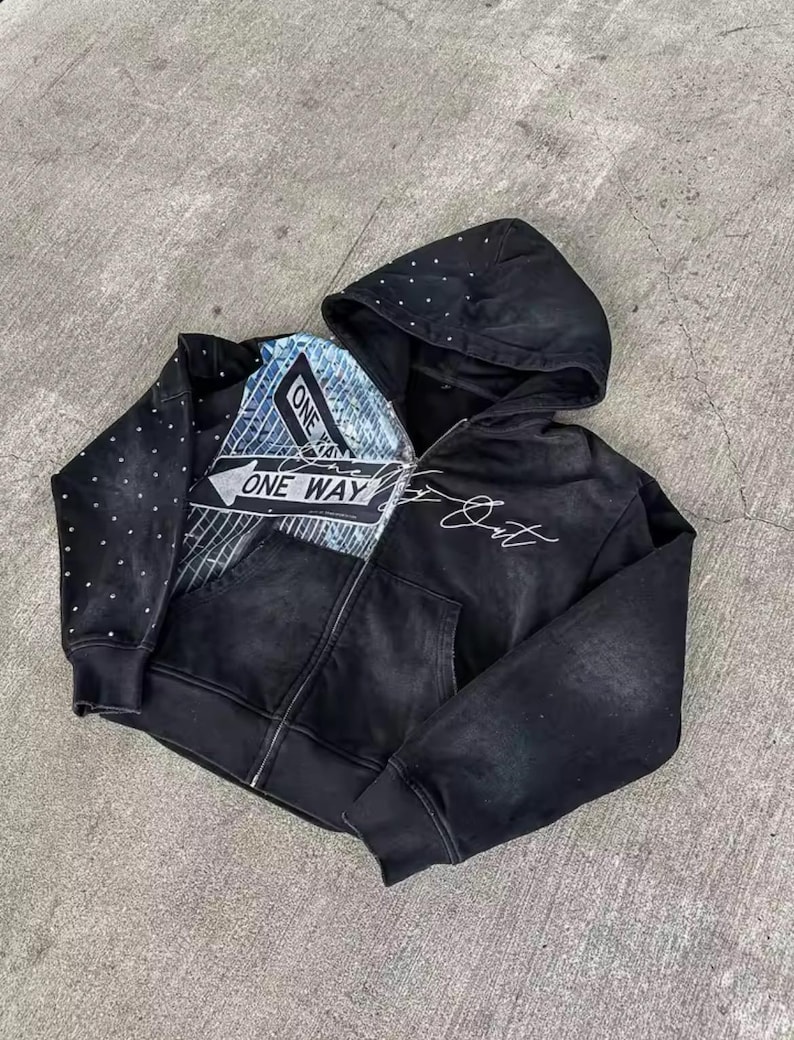 May include: Black zip-up hoodie with a distressed look. Features a "ONE WAY" graphic on the front, a dotted pattern on the left sleeve, and white script on the right side. The hood is also black.