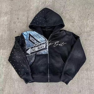 May include: Black zip-up hoodie with a hood and front pocket. The left side features a street sign graphic with "ONE WAY" text, while the right side has the text "Go Out". The hood is embellished with small, silver studs.