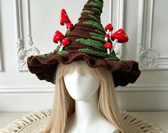 May include: A tall, pointed crochet hat in dark brown with textured green accents and several small, bright red mushrooms with white spots attached to the exterior. The hat features a wide, wavy brim and a curled tip at the very top.