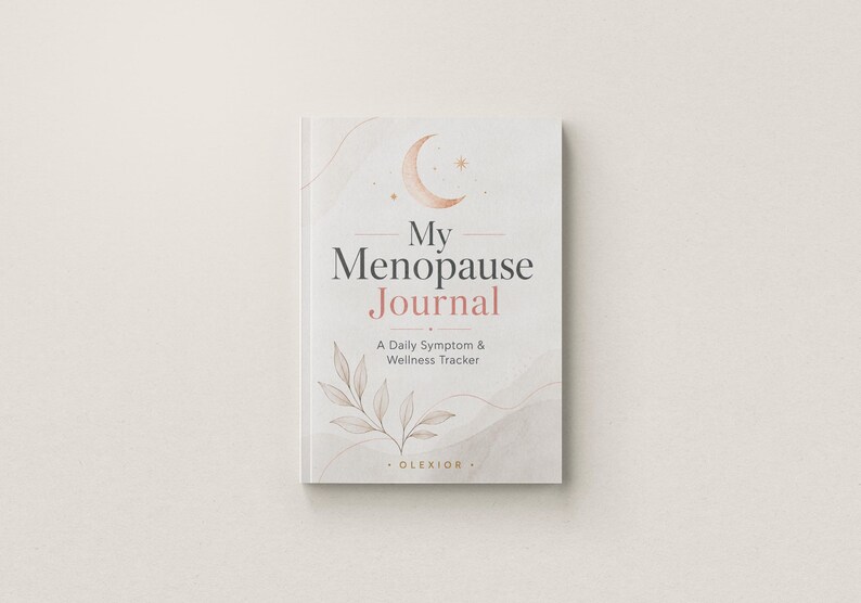 May include: A white journal titled My Menopause Journal: A Daily Symptom & Wellness Tracker. The cover features a crescent moon, small stars, and a delicate leaf illustration in soft peach and grey tones, with the brand name OLEXIOR at the bottom.