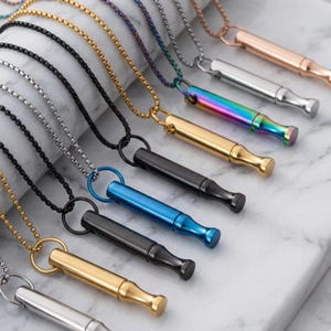 May include: A collection of cylindrical pendant necklaces featuring various metallic finishes including gold, silver, rose gold, black, blue, and iridescent rainbow. Each pendant is attached to a matching metal chain, showcasing a sleek, uniform design.