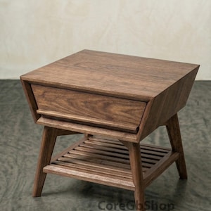 Könnte beinhalten: Ein Beistelltisch aus Holz im Mid-Century-Modern-Stil mit einer Schublade und einem Lattenregal. Der Tisch ist aus dunkelbraunem Holz gefertigt und hat abgewinkelte Beine. Die Schublade ist bündig mit der Oberseite. Der Tisch ist etwa 61 cm hoch.
