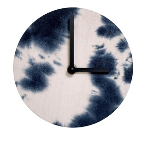 May include: Circular wall clock with a tie-dye pattern in blue and white. The clock has black hands and a black mechanism. The clock face displays a distinctive, artistic design, perfect for a modern interior.