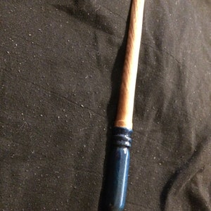 May include: A wooden wand with a blue painted tip. The wand is approximately 30 cm long and has a natural wood finish.