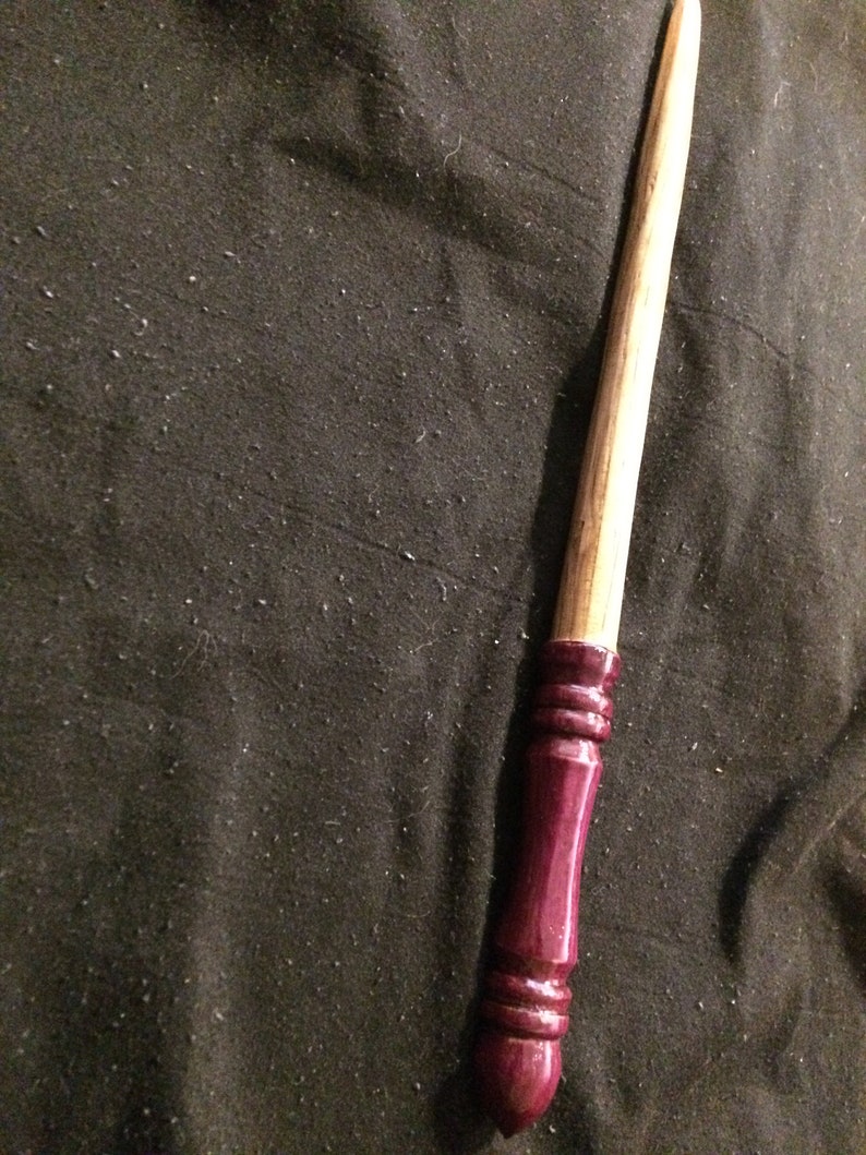 May include: A wooden wand with a dark burgundy painted handle. The wand is approximately 30 cm long.