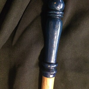 May include: A wooden wand with a dark blue painted tip and a natural wood handle.