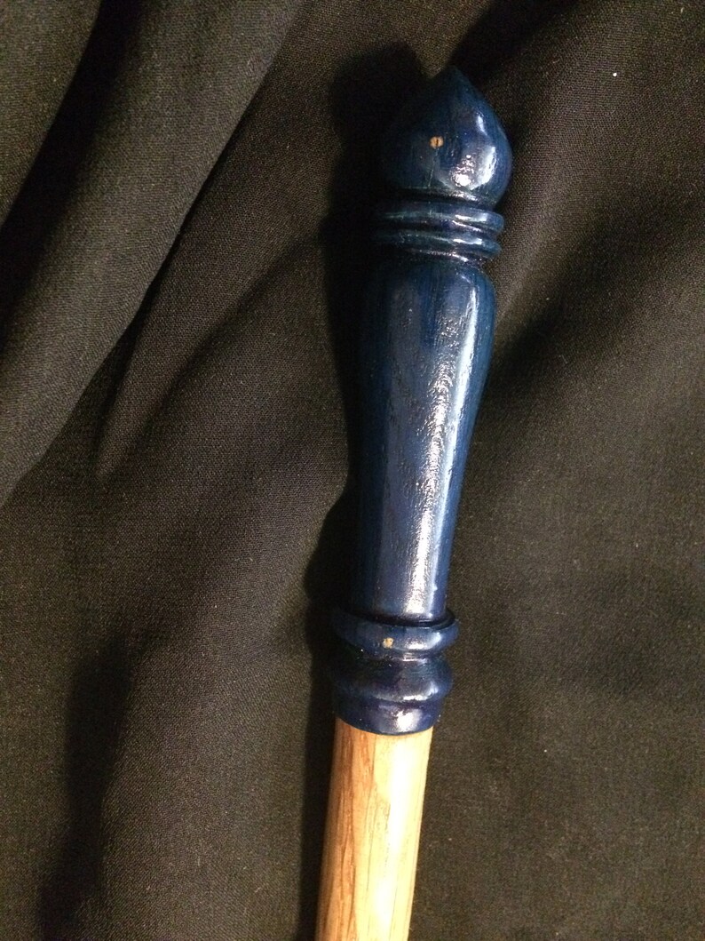 May include: A wooden wand with a dark blue painted tip and a natural wood handle.