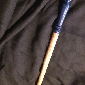May include: A wooden wand with a dark blue painted tip. The wand is approximately 30 cm long and has a smooth, natural finish.