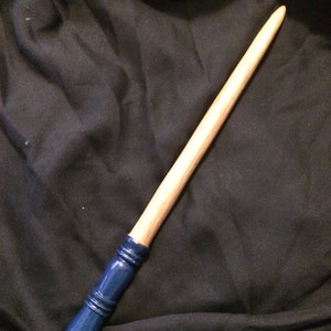 May include: A wooden wand with a blue painted tip. The wand is approximately 35 cm long and has a smooth, natural finish.