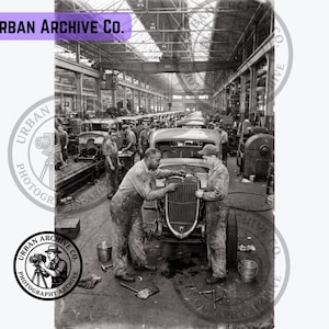 Peut inclure: Une photographie historique en noir et blanc montrant une chaîne de montage automobile industrielle avec des ouvriers en salopette assemblant des châssis de voiture. Le texte Urban Archive Co. apparaît en haut à gauche et un logo circulaire en bas à gauche.