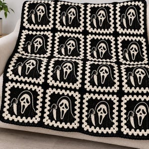May include: A black and white crochet blanket featuring a repeating pattern of sixteen square motifs. Each square displays a ghost-like figure with a white mask and a black hooded robe, holding a white knife, framed by a cream-colored border.