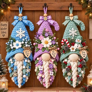 May include: Three crocheted gnome wall hangings with pointed hats. The blue gnome features a snowflake and Let It Snow tag. The purple gnome has floral accents and a Be Kind tag. The green gnome includes a snowman and Stay Cozy tag.