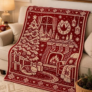May include: A rectangular throw blanket in deep red and cream featuring a knitted Christmas scene. The design includes a decorated tree, wrapped gifts, a sleeping cat, a fireplace with stockings, a wreath, hanging lanterns, and a window.
