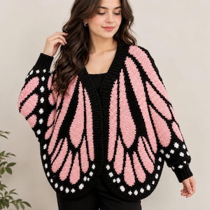 Può includere: Un cardigan a maniche lunghe aperto sul davanti con un motivo ad ali di farfalla nero e rosa. Il capo in maglia presenta un bordo a coste nero tinta unita lungo lo scollo e i polsini, con piccoli punti bianchi integrati nelle sezioni nere.