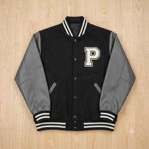 May include: A black varsity jacket featuring grey sleeves, a white letter P patch on the left chest, and a front button closure. The collar, cuffs, and hem are ribbed with white stripes. The jacket has two side pockets and a quilted interior lining.