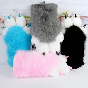 Puede incluir: Cuatro guantes de felpa con forma de pata de animal en piel sintética larga de color azul, gris, rosa y negro. Cada guante tiene dedos acolchados blancos con garras puntiagudas en colores a juego, incluyendo puntas azules, negras y rosas.