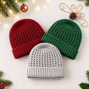 May include: Three knit beanies in red, green, and light gray. Each hat features a textured waffle-stitch pattern on the crown and a ribbed cuff at the base. The beanies are arranged in a triangular formation, showcasing their consistent design.