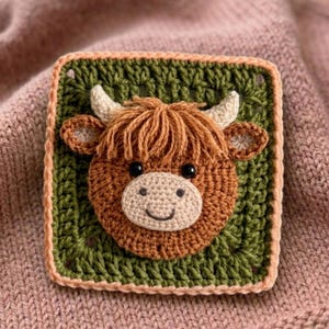 May include: A crocheted square with a Highland cow motif. The cow has brown fur, a beige muzzle, and small horns. The square is green with a peach border, set against a pink background. The cow's eyes are black.