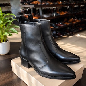 May include: A pair of black leather ankle boots with a pointed toe, a low block heel, and a vertical pull tab at the back of the collar. The boots feature smooth leather construction with visible stitching along the side panels and a solid black sole.