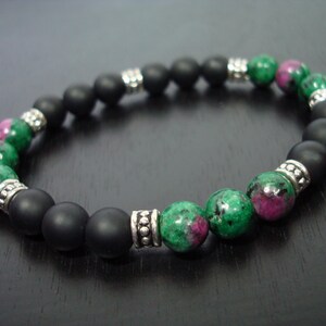May include: A bracelet with matte black onyx beads and green and pink ruby zoisite beads. Silver-toned metal spacers are featured in this handcrafted jewellery.