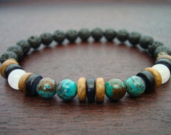 Puede incluir: Un brazalete con cuentas de roca volcánica negra, madera marrón, piedra blanca y turquesa.