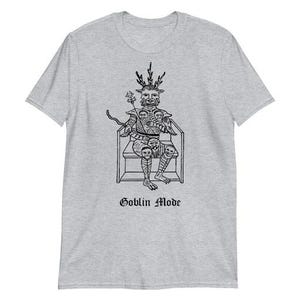 May include: A light gray t-shirt featuring a black illustration of a horned figure seated on a throne, holding a flower. The text "Goblin Mode" is printed below the illustration.