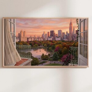Könnte beinhalten: Ein rechteckiger Wandkunstdruck, der den Blick aus einem offenen Fenster auf eine Skyline und einen Park mit See bei Sonnenuntergang zeigt. Die Szene umfasst einen hellen Vorhang, ein grünes Balkongeländer aus Metall und herbstliche Bäume.