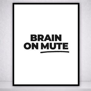 Könnte beinhalten: Gerahmter Kunstdruck mit dem Text "BRAIN ON MUTE" in fetten, schwarzen Buchstaben. Der Text ist auf weißem Hintergrund zentriert und mit einem schwarzen Strich unterstrichen. Der Druck ist in einem schwarzen Rahmen gefasst.