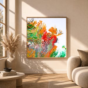 Puede incluir: Impresión artística abstracta en un marco de madera. La obra presenta una vibrante mezcla de colores, incluyendo naranja, rojo, verde y blanco, creando una composición dinámica y texturizada. La pieza se exhibe en una habitación bien iluminada con tonos neutros.
