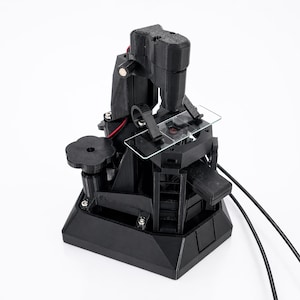 May include: A black 3D-printed microscope with a stage for slides and a focusing mechanism. The microscope has a tall, angled arm and a base with a circular adjustment knob. Wires extend from the device.