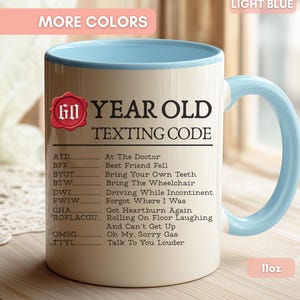May include: A light blue and cream ceramic mug with an 11oz capacity. The mug features a red wax seal graphic with the number 60 and the text 60 YEAR OLD TEXTING CODE, followed by a list of humorous acronym definitions like ATD, BFF, and TTYL.