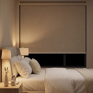 May include: A bedroom scene featuring a bed with white bedding, pillows, and a nightstand with a lamp. A neutral-toned roller shade covers the window. The room is lit with warm, soft lighting, creating a cozy atmosphere.