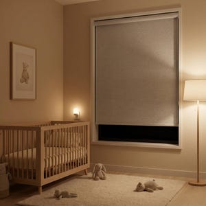 May include: A light grey roller blind installed inside a window frame, featuring a smooth, solid fabric texture. The blind is partially lowered, covering the upper portion of the window while leaving a dark rectangular gap at the bottom.