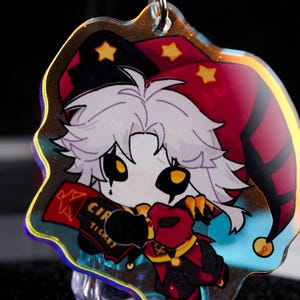 May include: A colorful acrylic charm featuring a cartoon jester character. The jester wears a red and black hat with gold stars and a matching outfit. The charm holds a red ticket that reads "CIR TICKET".