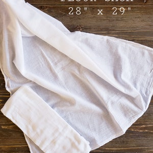 May include: White cotton flour sack measuring 28 inches by 29 inches, folded on a wooden surface.