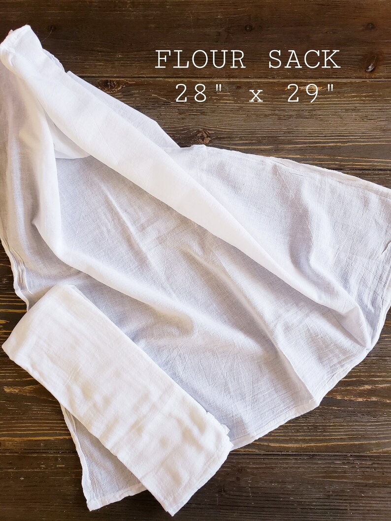 May include: White cotton flour sack measuring 28 inches by 29 inches, folded on a wooden surface.