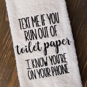 May include: White hand towel with black embroidered text that reads "Text me if you run out of toilet paper I know you're on your phone."