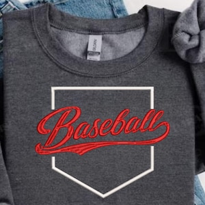 May include: Dark gray sweatshirt with the word "Baseball" in red script inside a white home plate outline. The sweatshirt is folded, with the sleeves rolled up. The fabric appears to be a soft, comfortable material.