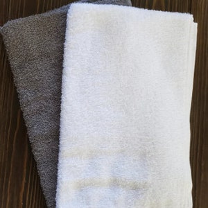 May include: Two towels, one gray and one white, folded on a wooden surface. The text "powder room 14" x 8" is visible above the towels.