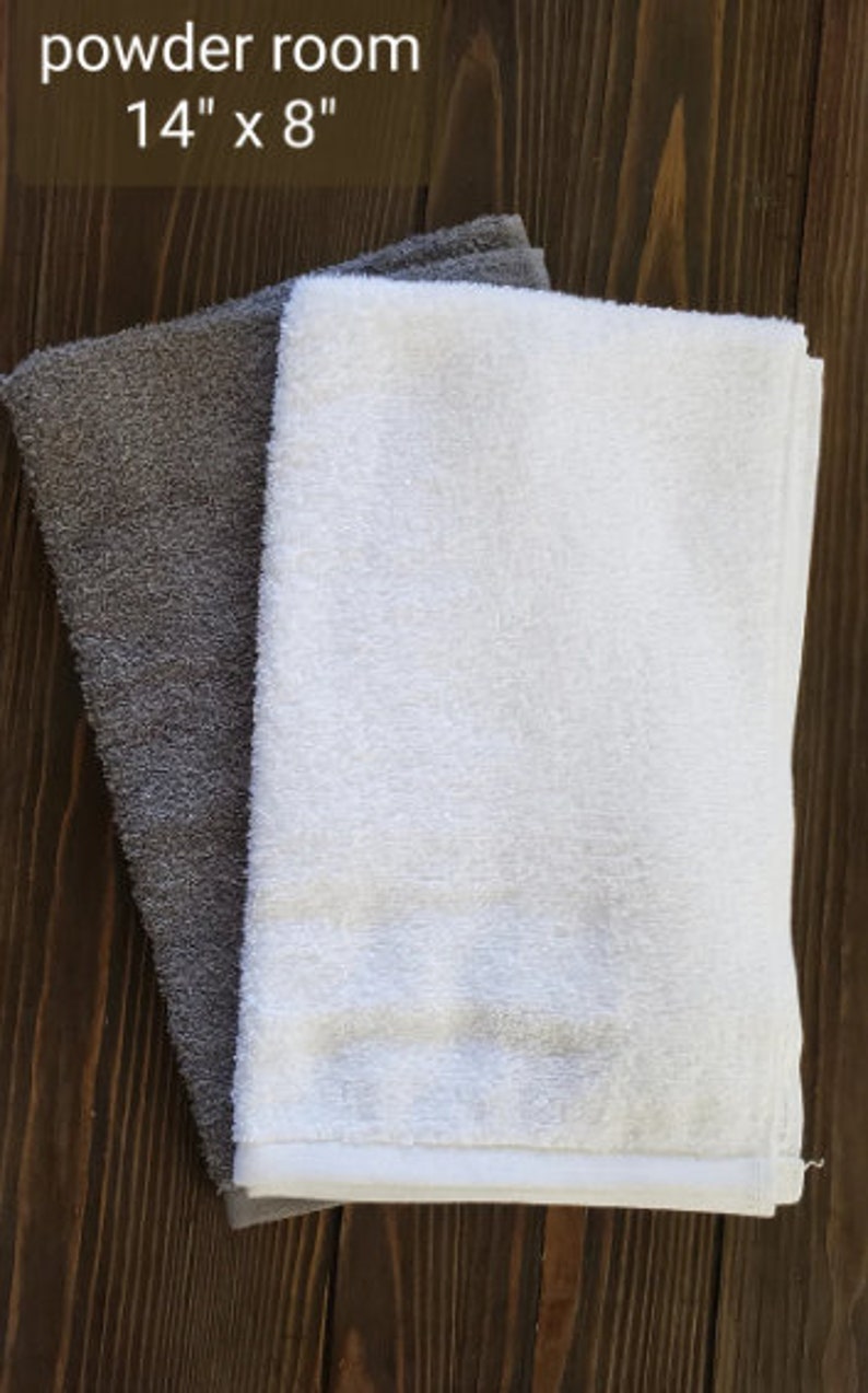 May include: Two towels, one gray and one white, folded on a wooden surface. The text "powder room 14" x 8" is visible above the towels.