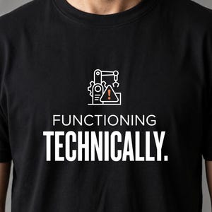 May include: A black short-sleeved t-shirt featuring a white graphic of a robotic arm with a gear and an orange warning triangle. Below the graphic, the text reads "FUNCTIONING" in white and "TECHNICALLY." in large white capital letters.