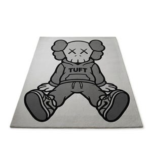 K&ouml;nnte beinhalten: Ein rechteckiger, hellgrauer Teppich mit einer Cartoonfigur in sitzender Position. Die Figur tr&auml;gt einen grauen Kapuzenpullover mit dem Wort "TUFT" auf der Vorderseite, eine graue Hose und graue Turnschuhe. Das Gesicht der Figur hat zwei "X" als Augen.