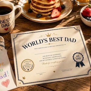 Può includere: Un certificato color crema intitolato World's Best Dad con testo blu scuro, un'icona a corona dorata e un sigillo con la scritta #1 Dad. Il documento include righe per la data e la firma, circondato da un bordo decorativo su una superficie in legno.
